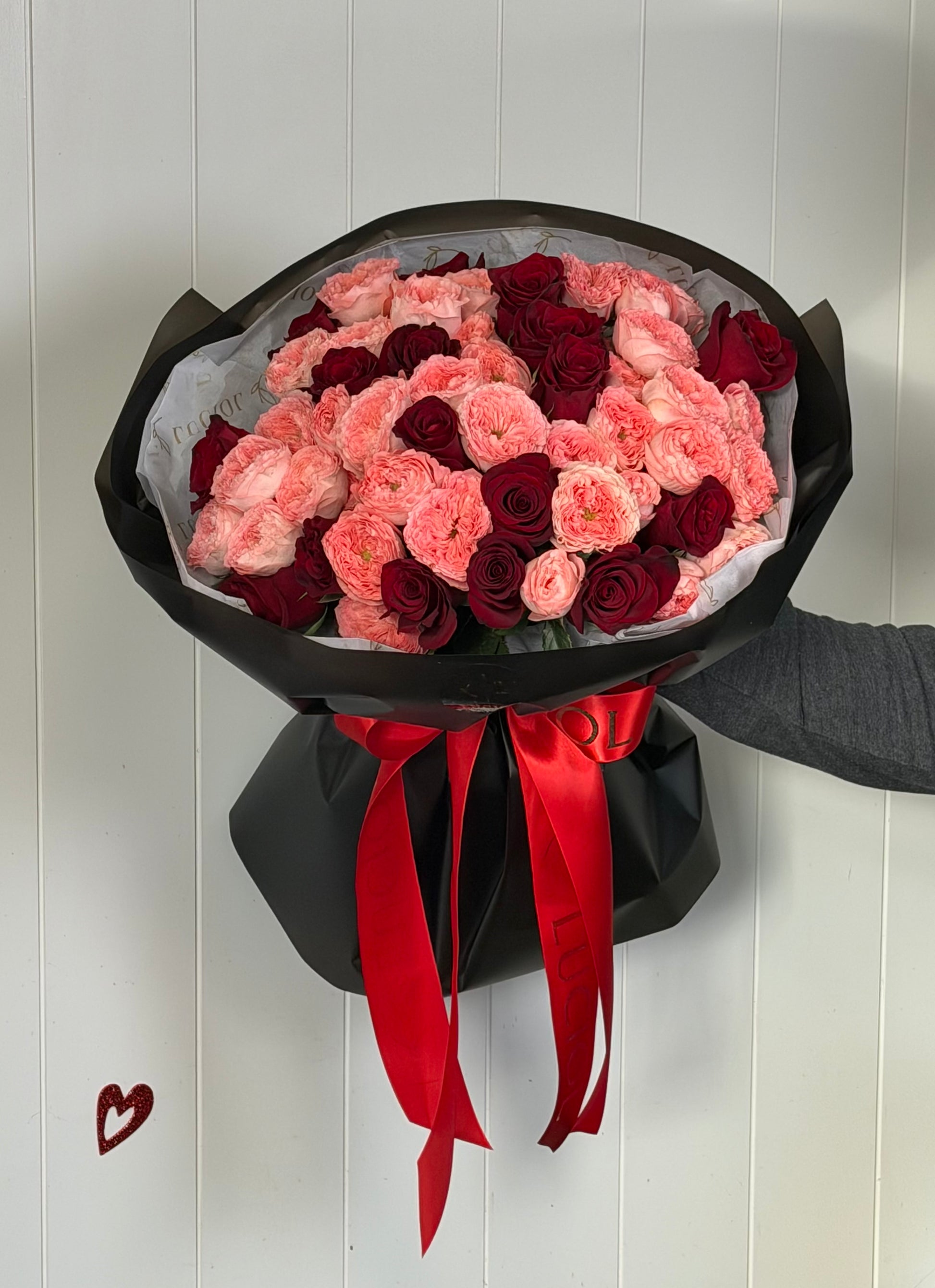 Valentine’s Day bouquet with red roses and Isabella spray roses in black wrapping by LUCIOL